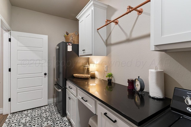 9111 Highland Springs Dr, Amarillo, TX 79119 - kitchen featuring freestanding refrigerator, white cabinetry, dark countertops, and baseboards