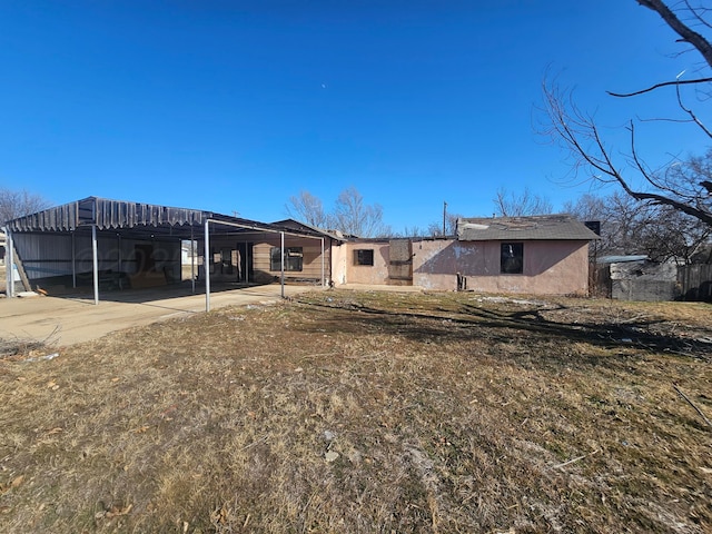 back of house featuring stucco siding and a yard