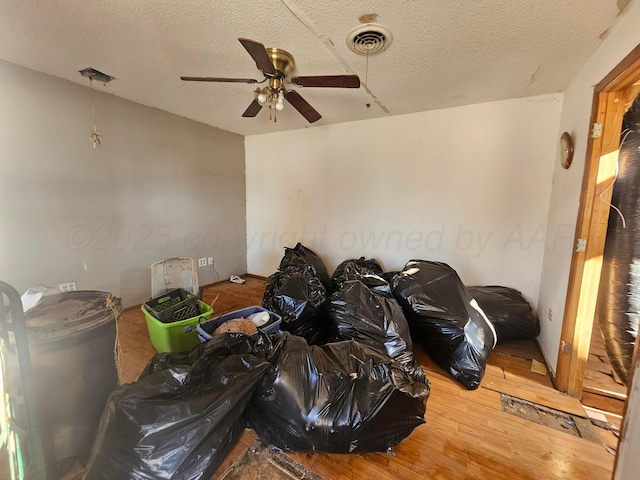 misc room with a textured ceiling, visible vents, and wood finished floors