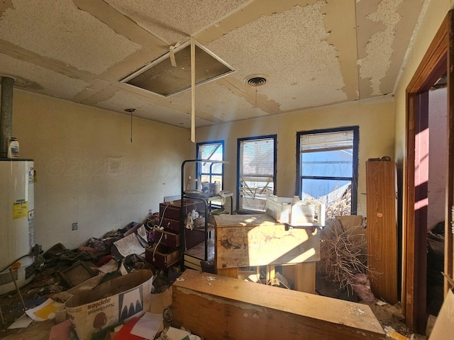 miscellaneous room with attic access, visible vents, and gas water heater