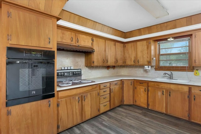 kitchen with dark wood-type flooring, oven, sink, decorative backsplash, and cooktop