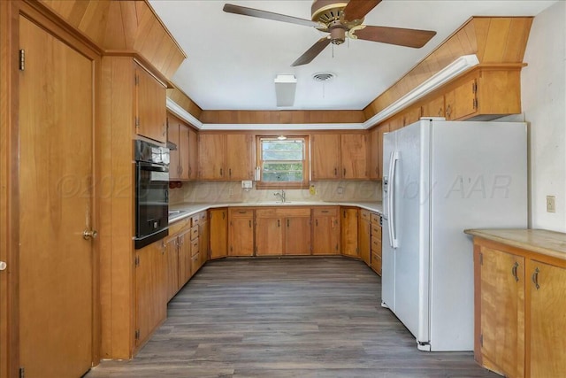 kitchen featuring white refrigerator with ice dispenser, backsplash, oven, ceiling fan, and dark hardwood / wood-style flooring