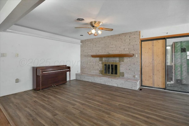 unfurnished living room with a barn door, ceiling fan, a fireplace, and dark hardwood / wood-style flooring