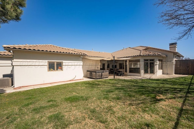rear view of house with fence, a tiled roof, a patio area, and a hot tub