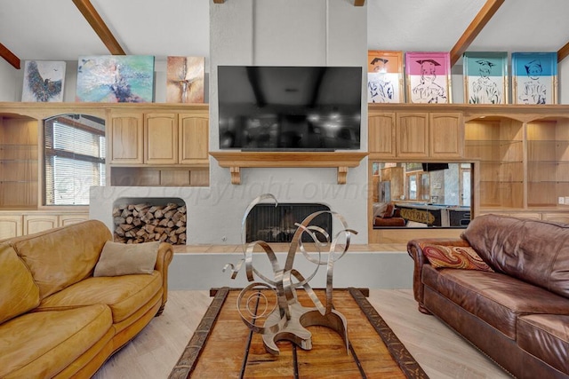 living room with beamed ceiling and a fireplace with raised hearth