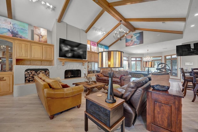 living room featuring beamed ceiling, an inviting chandelier, a premium fireplace, and light wood finished floors
