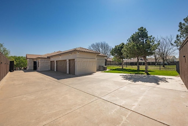 garage featuring fence, cooling unit, and concrete driveway