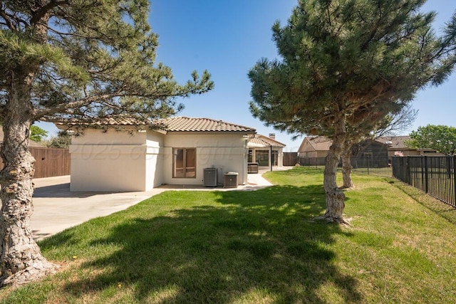 rear view of house featuring a patio, a fenced backyard, a lawn, central AC, and stucco siding
