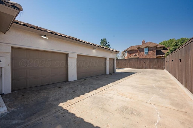 garage with concrete driveway and fence