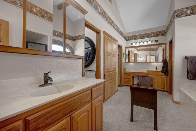 full bathroom featuring a relaxing tiled tub, vaulted ceiling, two vanities, and a sink