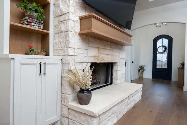 interior space with baseboards, a fireplace, wood finished floors, and arched walkways