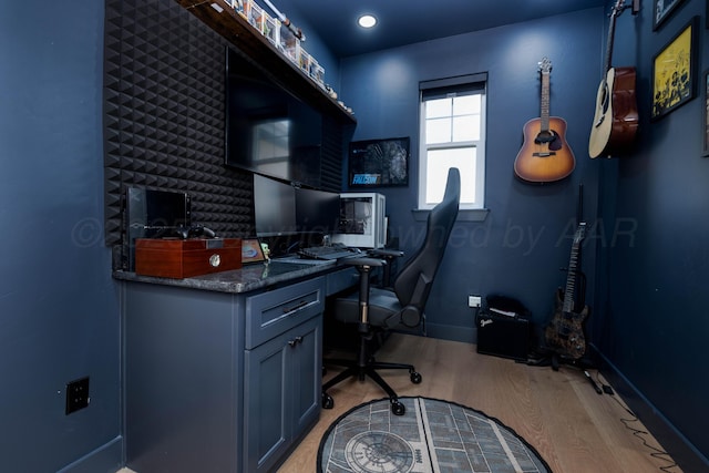 office space featuring light wood-type flooring, baseboards, and built in desk