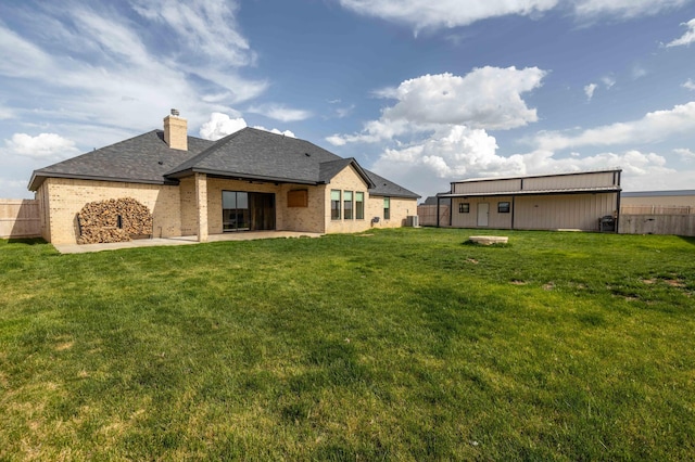 rear view of property featuring a chimney, a fenced backyard, a yard, a patio, and brick siding