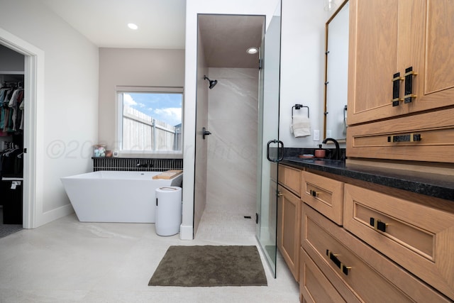 full bath with a spacious closet, a freestanding tub, vanity, and a stall shower
