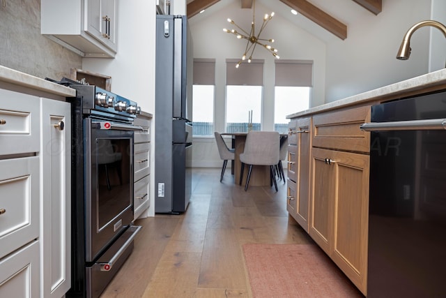 kitchen featuring light wood-type flooring, appliances with stainless steel finishes, vaulted ceiling with beams, and a notable chandelier