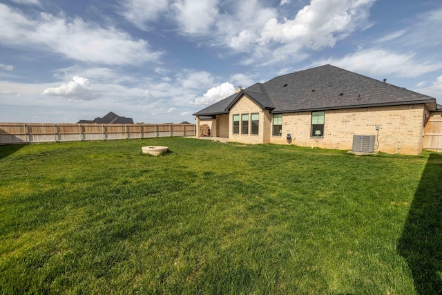 back of house with brick siding, a yard, central air condition unit, and a fenced backyard