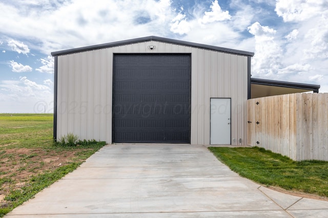 view of outdoor structure with driveway, an outbuilding, and fence