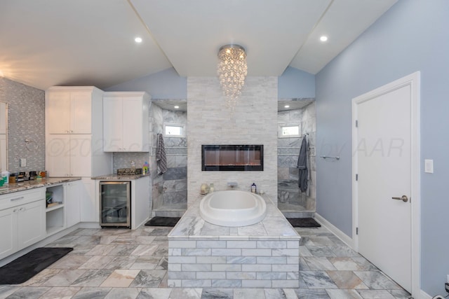 2 Altamira St, Borger, TX 79007 - bathroom with beverage cooler, vaulted ceiling, a bath, a walk in shower, and a glass covered fireplace