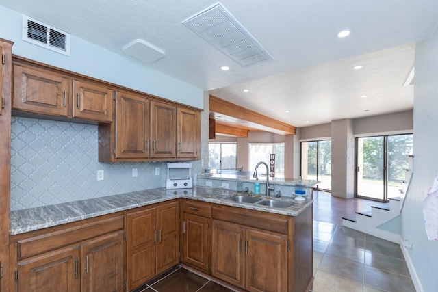 2 Altamira St, Borger, TX 79007 - kitchen with a sink, a peninsula, dark tile patterned floors, decorative backsplash, and recessed lighting