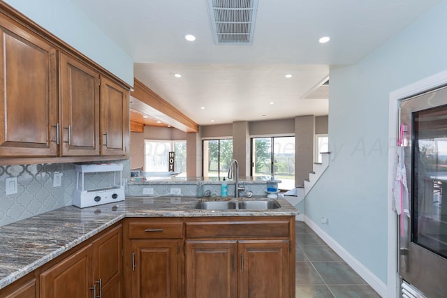 2 Altamira St, Borger, TX 79007 - kitchen with a sink, backsplash, dark tile patterned flooring, a peninsula, and stone countertops