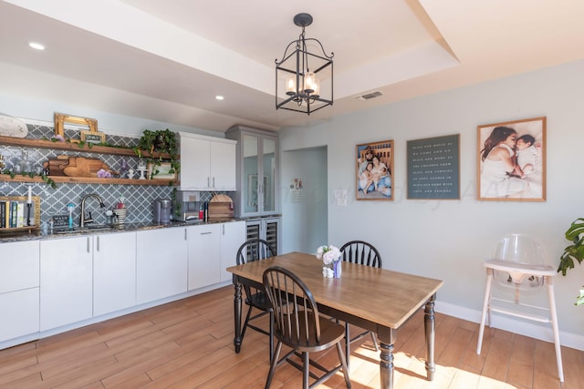 2 Altamira St, Borger, TX 79007 - dining room featuring light wood-style flooring, a tray ceiling, wine cooler, a chandelier, and recessed lighting