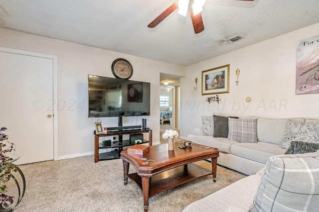 carpeted living room featuring ceiling fan and a textured ceiling