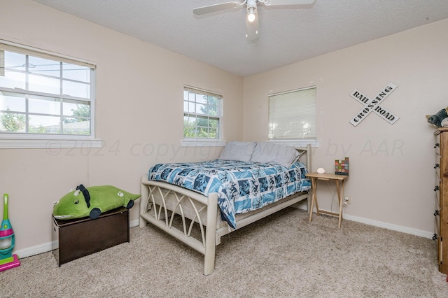 carpeted bedroom with ceiling fan and a textured ceiling