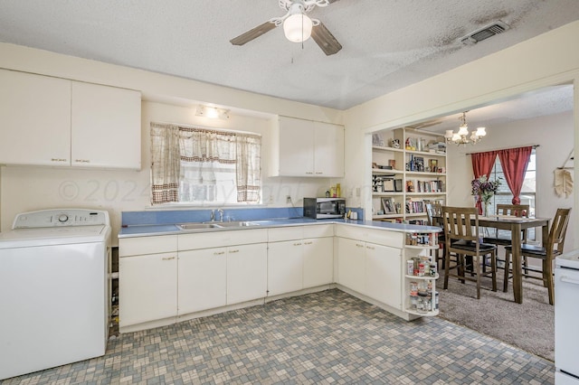 kitchen featuring sink, white cabinetry, hanging light fixtures, a textured ceiling, and washer / dryer