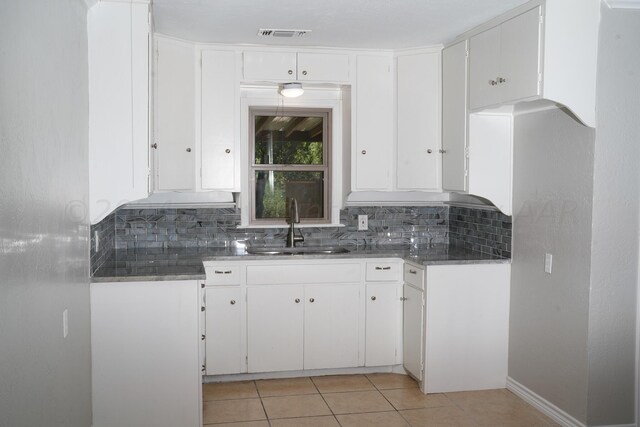 709 N Wells St, Pampa, TX 79065 - kitchen featuring tasteful backsplash, light tile patterned floors, sink, and white cabinets