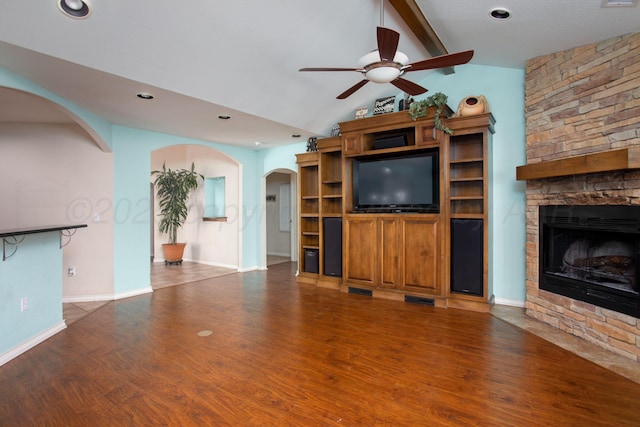103 N Timbercreek Dr, Amarillo, TX 79118 - unfurnished living room with wood finished floors, a stone fireplace, a ceiling fan, arched walkways, and lofted ceiling with beams