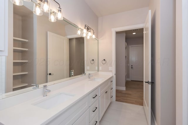 bathroom featuring double vanity, baseboards, and a sink