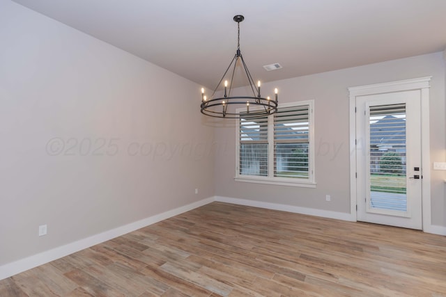 unfurnished room featuring baseboards, visible vents, light wood finished floors, and a chandelier
