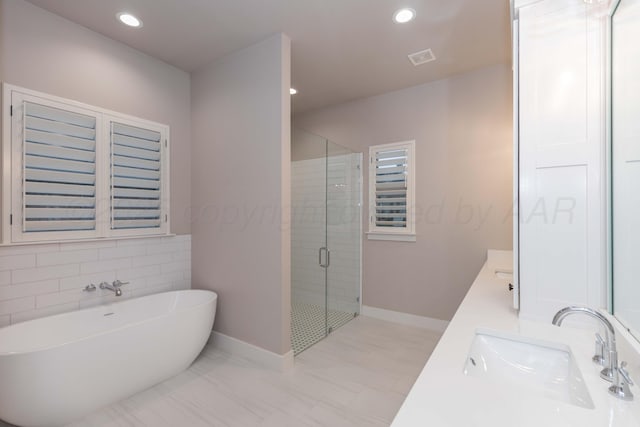 bathroom featuring a sink, double vanity, recessed lighting, a freestanding tub, and a shower stall