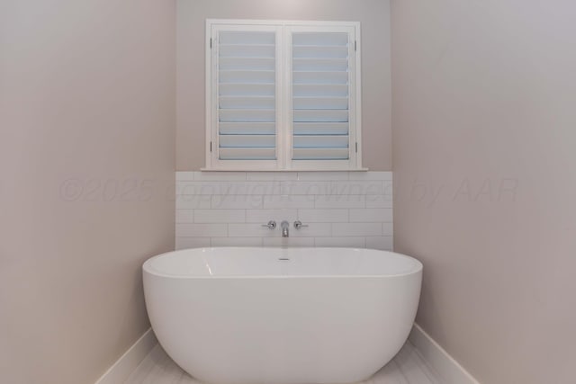 full bath featuring baseboards and a freestanding tub