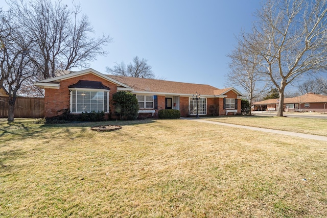 ranch-style house featuring a front yard, brick siding, and fence