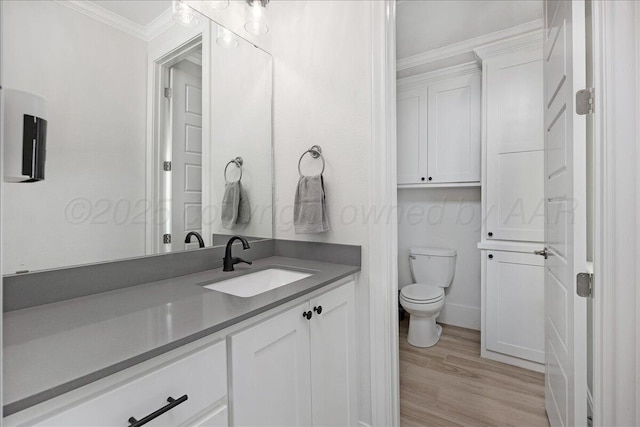 bathroom featuring vanity, hardwood / wood-style flooring, ornamental molding, and toilet