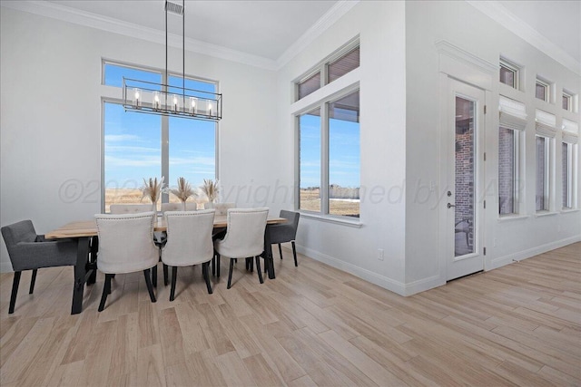 dining area with a notable chandelier, ornamental molding, and light hardwood / wood-style floors