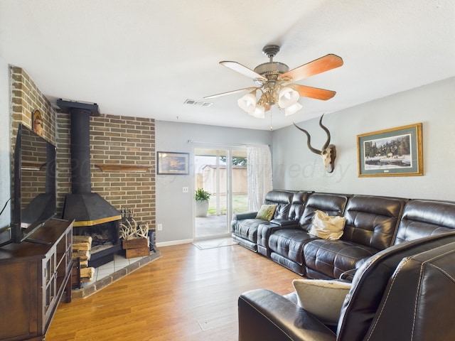 1409 Bailey Ave, Dumas, TX 79029 - living room featuring a wood stove, wood finished floors, and ceiling fan