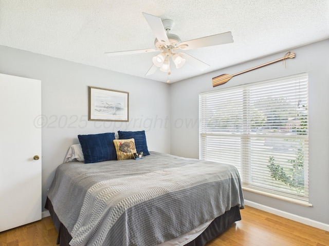 1409 Bailey Ave, Dumas, TX 79029 - bedroom featuring multiple windows, light wood-style flooring, a ceiling fan, and a textured ceiling