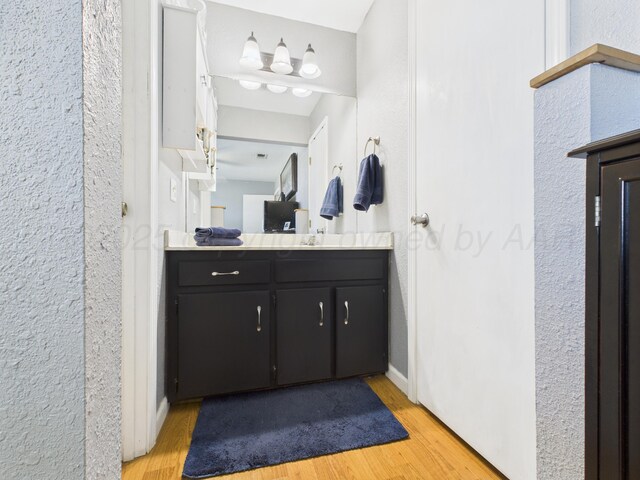 1409 Bailey Ave, Dumas, TX 79029 - bathroom with wood finished floors, vanity, and a textured wall