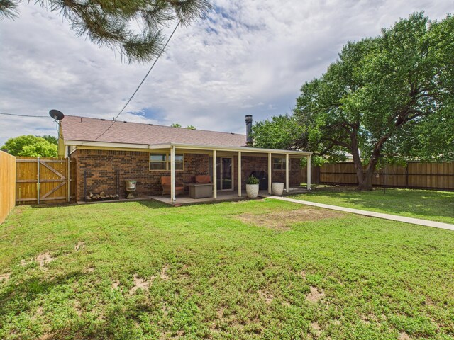 1409 Bailey Ave, Dumas, TX 79029 - rear view of property with a fenced backyard, brick siding, a patio, and a gate