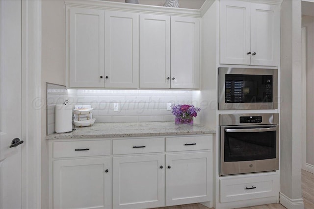 9109 Staten Island St, Amarillo, TX 79119 - kitchen with appliances with stainless steel finishes, white cabinetry, light stone countertops, and tasteful backsplash