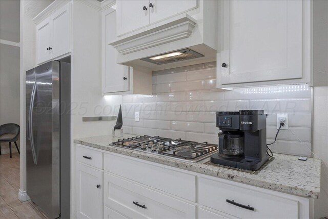 9109 Staten Island St, Amarillo, TX 79119 - kitchen with appliances with stainless steel finishes, premium range hood, backsplash, white cabinetry, and light stone countertops