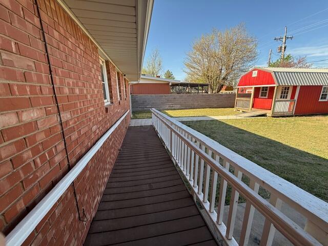 view of side of home with an outdoor structure, a yard, brick siding, and a fenced backyard