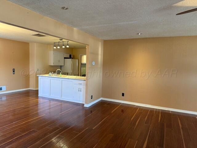 interior space with visible vents, baseboards, a textured ceiling, and dark wood-style flooring