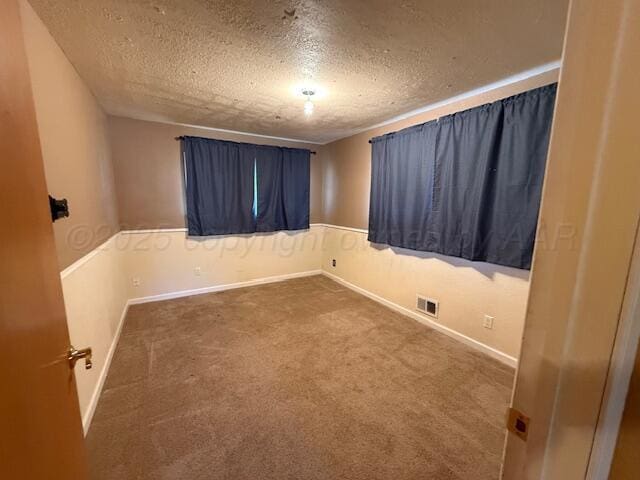 carpeted spare room featuring baseboards, a textured ceiling, and visible vents