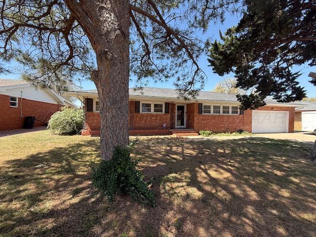 single story home with an attached garage, entry steps, a front lawn, and brick siding