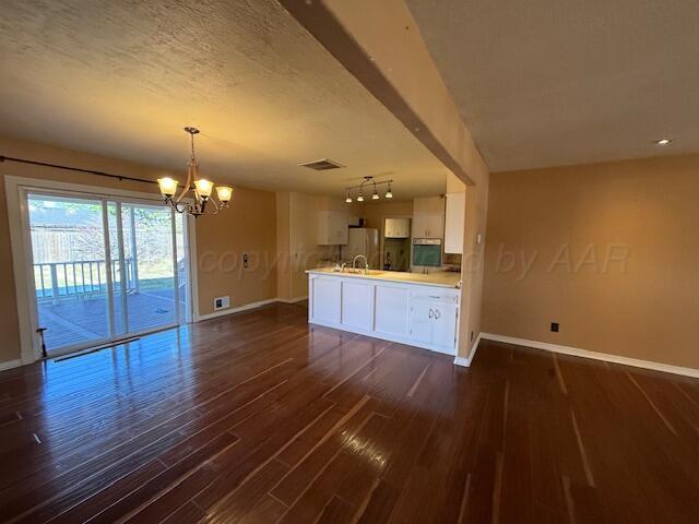 interior space with dark wood finished floors, visible vents, baseboards, and a notable chandelier