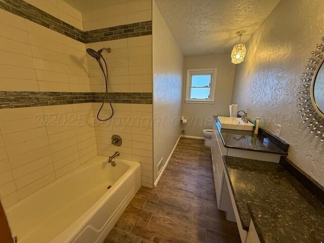full bath featuring a textured ceiling, toilet, shower / bathing tub combination, baseboards, and vanity