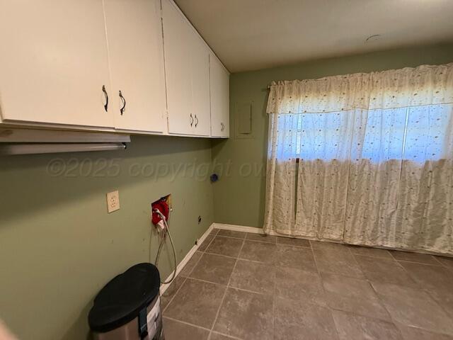 laundry area with cabinet space, dark tile patterned floors, and baseboards